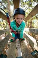 Little girl wearing helmet trying to cross obstacle in the forest