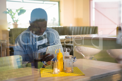 Young man using his tablet while having drink