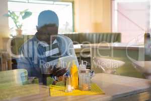 Young man using his tablet while having drink