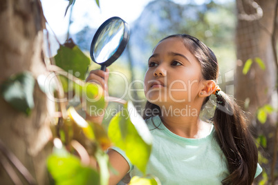 Little girl holding magnifying glass exploring nature