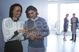 Male and female executives discussing over digital tablet