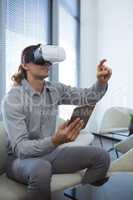 Male executive holding digital tablet while using virtual reality headset