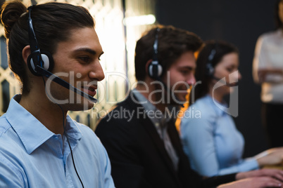 Business executives with headsets using computers at desk