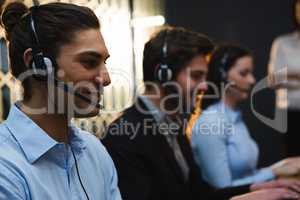 Business executives with headsets using computers at desk