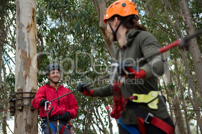 Hiker couple holding zip line cable in the forest