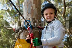 Little girl wearing helmet standing near zip line