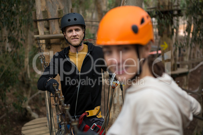 Smiling man wearing safety helmet standing and holding zip line in the forest