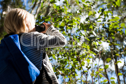 Little girl with bag pack enjoying nature with binoculars