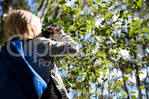 Little girl with bag pack enjoying nature with binoculars