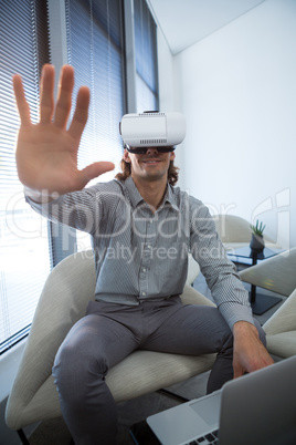 Male executive using laptop and virtual reality headset in waiting room