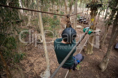 Man wearing safety helmet crossing zip line in the forest
