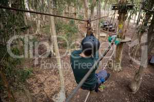 Man wearing safety helmet crossing zip line in the forest