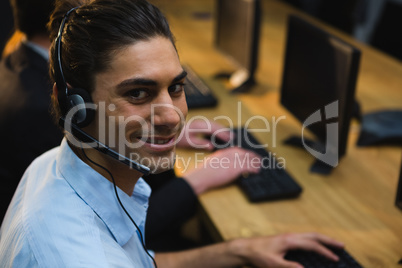 Male executive with headset using computer at desk