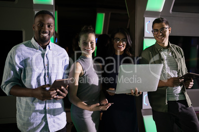 Portrait of business executives standing with laptop and digital tablet