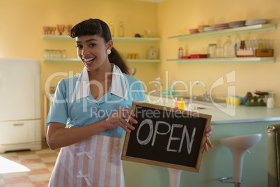 Waitress showing slate with open sign in restaurant