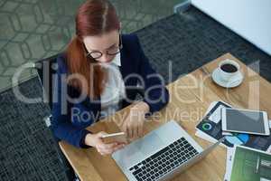 High angle view of female executive using mobile phone at desk