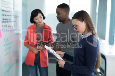 Female executive looking at graph with colleagues in background