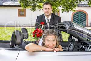 Bridal couple with wedding car