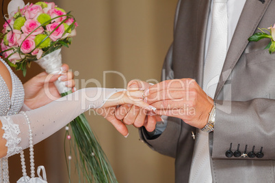 The groom has put on an engagement ring on a finger of the bride