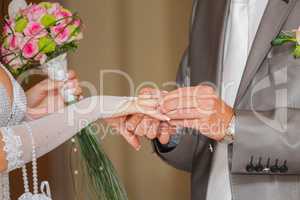 The groom has put on an engagement ring on a finger of the bride
