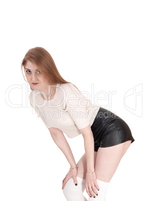 Woman standing in leather shorts bending forwards