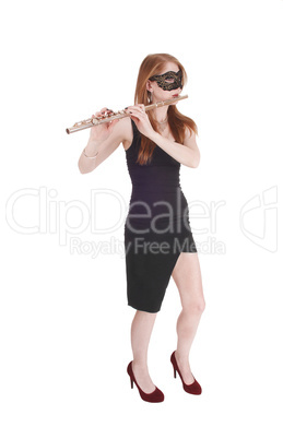 Woman standing, playing the flute wearing a mask