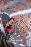 the girl in the pink shorts up the brick stairs, the girl climbs the stairs of red brick, the girl climbs the stairs inside the tower