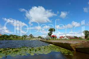 pontoon bridge across the river, a group of cyclists travelling on the bridge in the village outside the city in the summer