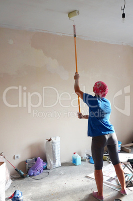 girl paints whitewash a ceiling, repair the apartment with his h