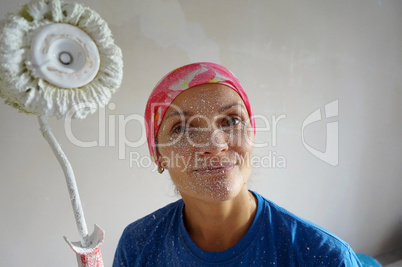 girl paints whitewash a ceiling, repair the apartment with his h