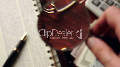 Ledger papers are watched with magnifier. Financial accounting concept. Selective focus.