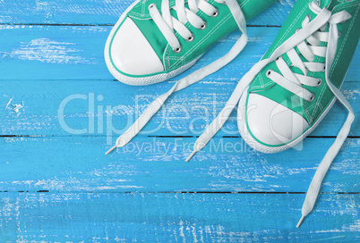 green textile sneakers on a blue wooden background