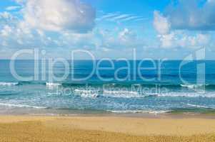 Deserted sandy beach of the Indian Ocean. In the blue sky cumulu