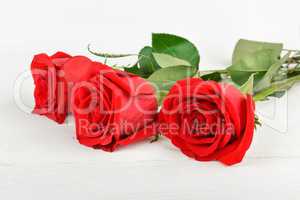 Beautiful red roses on a white wooden background. Free space for