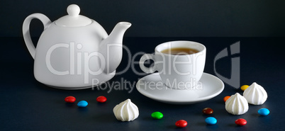 White cup and teapot on a black background.