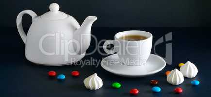 White cup and teapot on a black background.