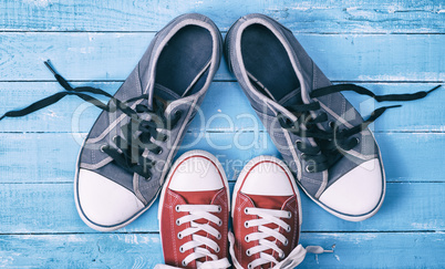 Two pairs of textile sneakers with loose laces stand opposite ea