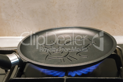 Cast-iron frying pan with ceramic coating is heated on the fire.