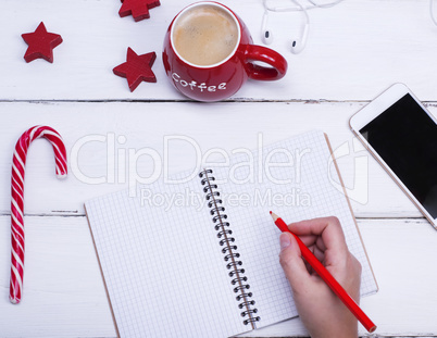 empty open notebook and female hand with a red wooden pencil