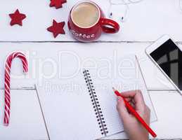 empty open notebook and female hand with a red wooden pencil