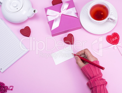 Female hand with a red pencil signs a greeting card