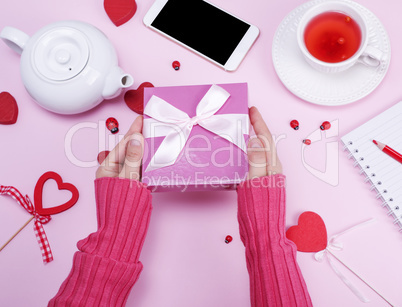 female hands hold packed box with a pink bow