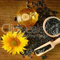 Seeds, oil and sunflower flower on a wooden background. Top view