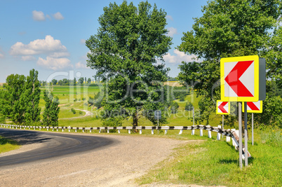 A winding road with steep turns in the hilly terrain. Green fiel