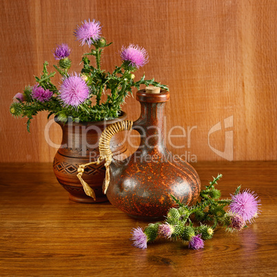 Oil and flowers of milk thistle on wooden .