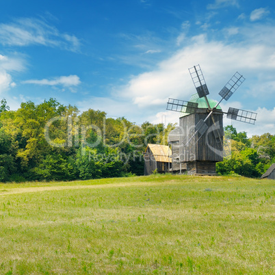Old wooden windmills in a field and sky.