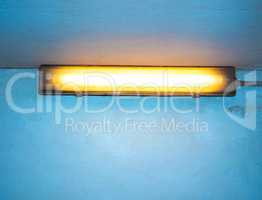 Yellow neon light over blue wall with copy space