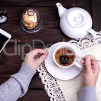 cup of black tea and two female hands