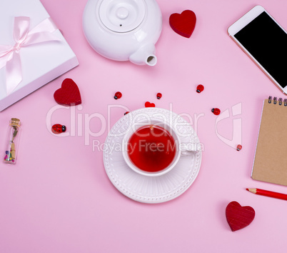 cup with tea from a berry of a viburnum on a rose background, to