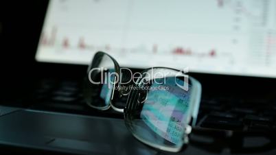 Online stock trading concept. Reflection with financial data on glasses.